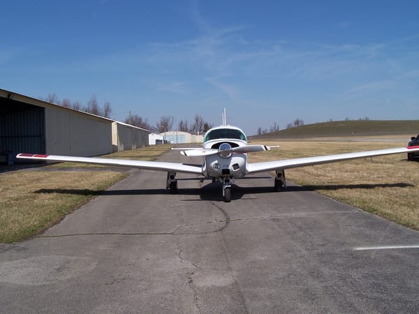 N3275F head-on on the taxiway, wings spread, hangars behind