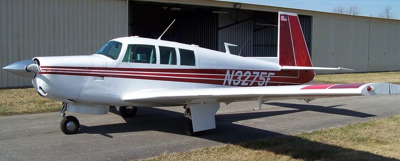 N3275F, the club's white and maroon Mooney M20F, parked on the ramp in front of a hangar